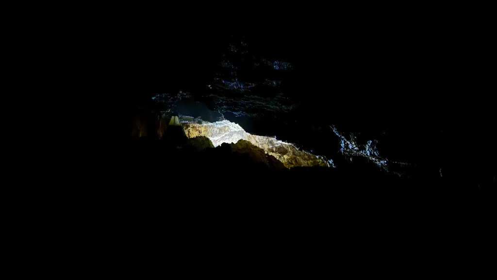 Silhouette devant la tente suspendue dans la Grotte Forestière — bivouac souterrain Ardèche